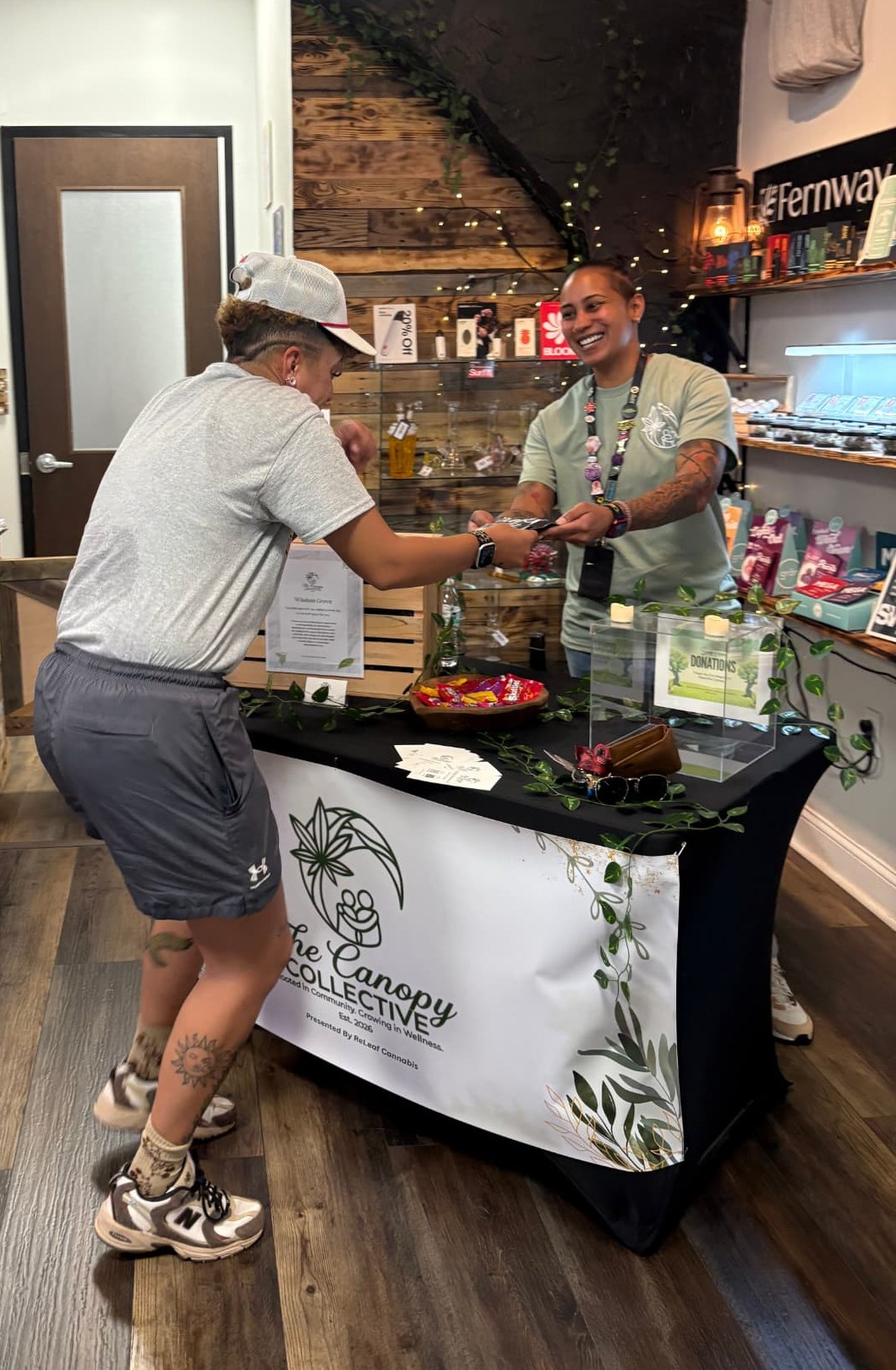 A community member welcoming a guest at The Canopy Collective table.