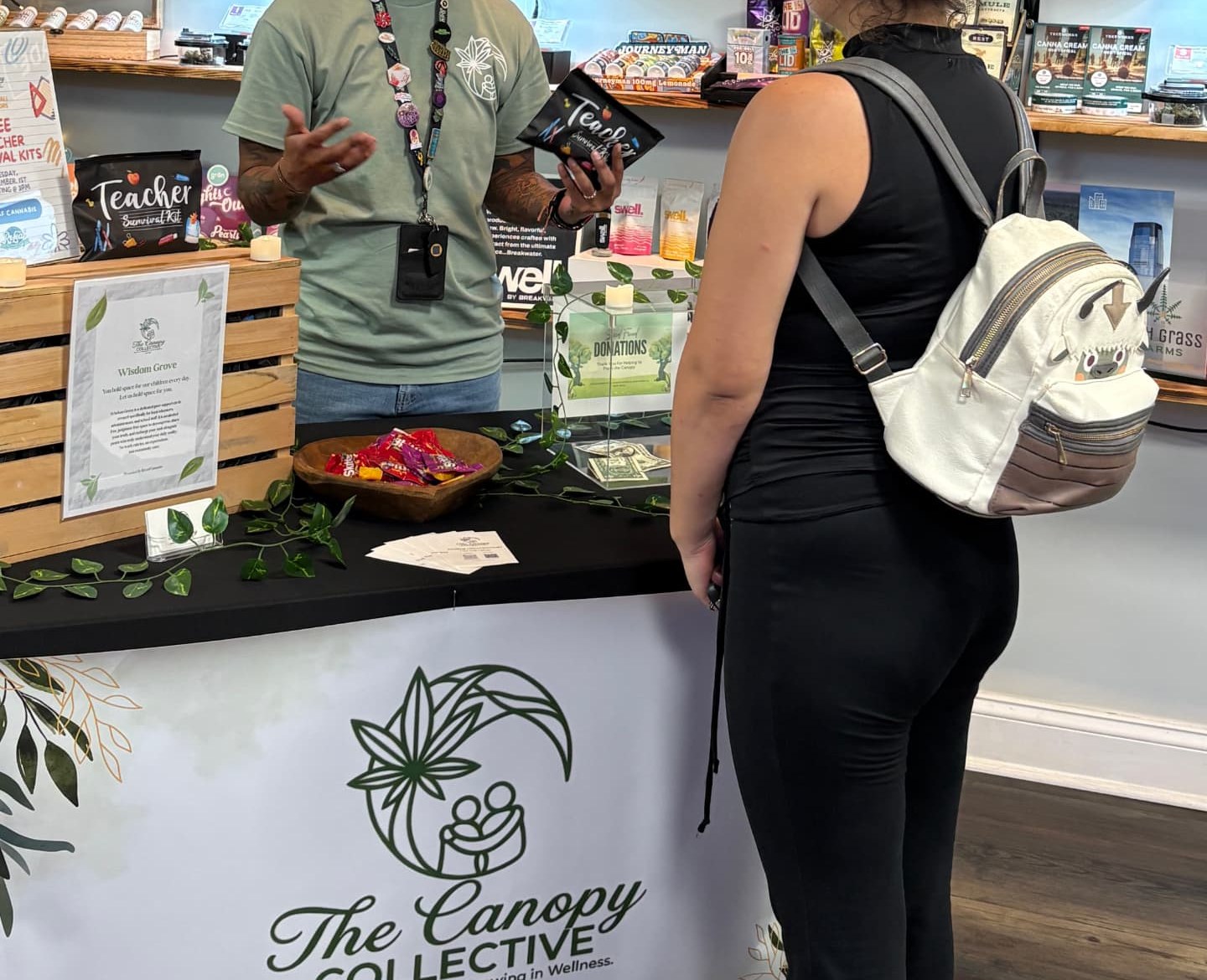 A community member talking with a guest across The Canopy Collective table.